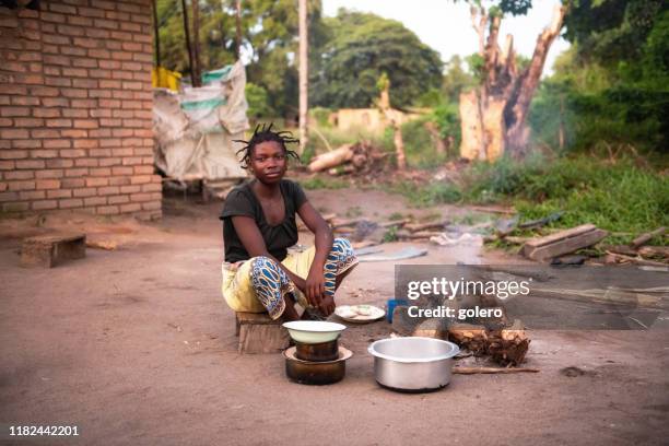 jonge afrikaanse vrouw koken buiten in de voorkant van bakstenen huis - malawi stockfoto's en -beelden