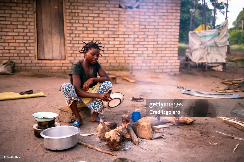 Young african woman cooking meal on the ground