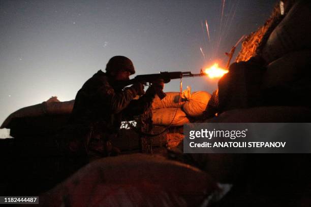 Ukrainian serviceman fires at Russia-backed separatists during night combat on the front line near Novolugansk in the Donetsk region on November 14,...