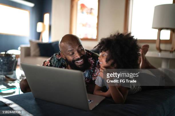 single father wacthing movie on a laptop with his daughter - family technology stock pictures, royalty-free photos & images