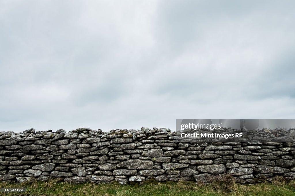 View of old dry stone wall under a cloudy sky.