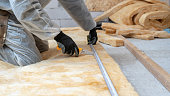 Professional workman installing thermal insulation rock wool under the roof