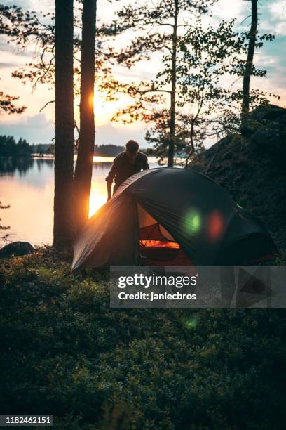 man is standing next to the tent standing in the forest - forest sweden stock pictures, royalty-free photos & images