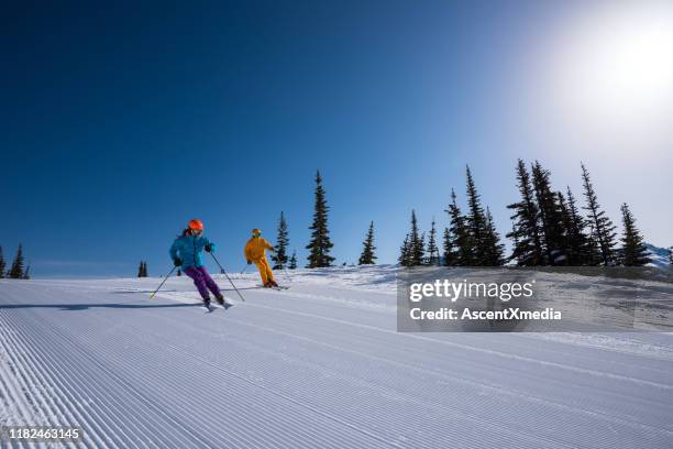 couple enjoying a ski vacation - alpine skiing downhill stock pictures, royalty-free photos & images