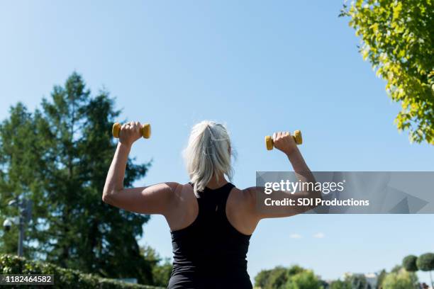 rear view of woman lifting weights - hand weight stock pictures, royalty-free photos & images