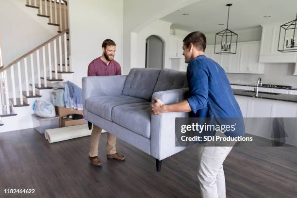 mannelijke verhuizers dragen een bank in huis - lifting stockfoto's en -beelden