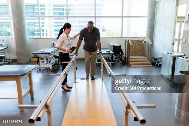 la fisioterapeuta femenina que cuida ayuda a la víctima del accidente cerebrovascular en el centro de rehabilitación - recovery fotografías e imágenes de stock