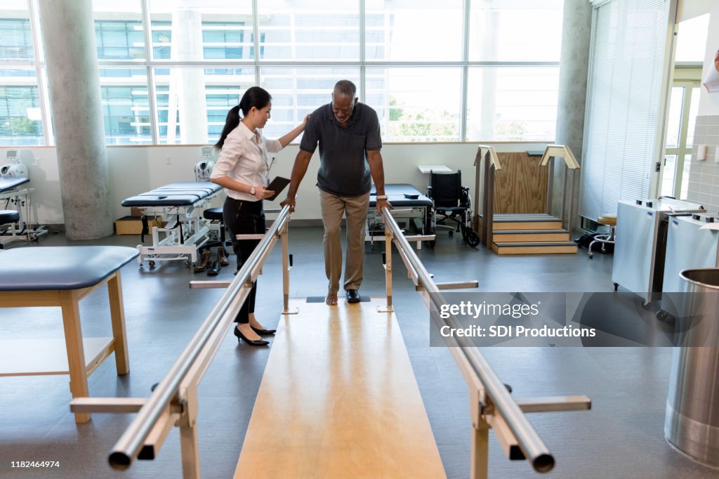 Caring female physical therapist helps stroke victim in rehab center