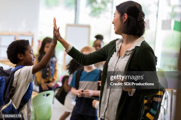 profesor de escuela primaria high fives estudiante - first day of school fotografías e imágenes de stock