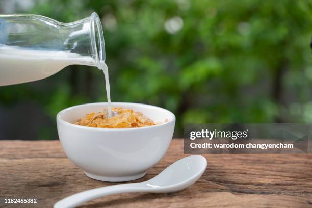 cornflakes and milk on wooden table at morning. - bowl of cereal stock pictures, royalty-free photos & images