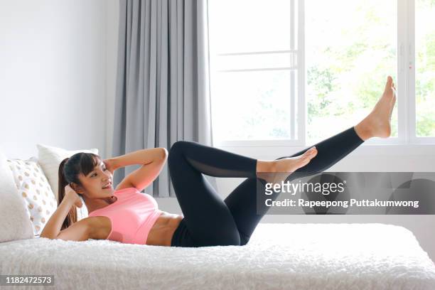woman doing exercise on bed at home. morning workout in bedroom. - morning bed stretch fotografías e imágenes de stock