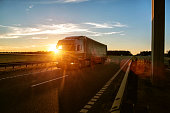 A road train carries a groupage cargo in a semi-trailer against the backdrop of a sunny sunset. Social transportation international, driver internships and hiring, background