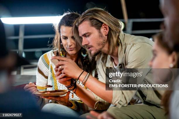 handsome man is showing some mobile phone pictures  to his girl friend - tap card stock pictures, royalty-free photos & images