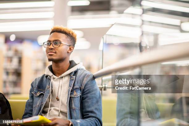 ein afroamerikanischer universitätsstudent, der in der bibliothek studiert stockfoto - teenager männlich stock-fotos und bilder