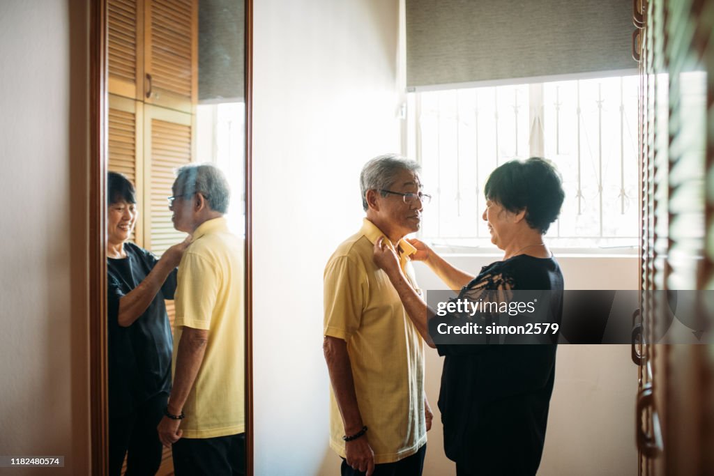 Mature Woman helping her husband to getting dressed