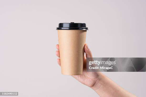 hand holding brown paper cup - coffee take away cup simple stock pictures, royalty-free photos & images