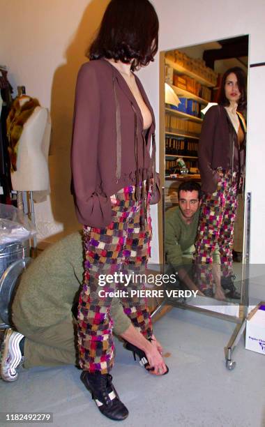 Le couturier français Hans de Foer ajuste, sur un modèle, une de ses créations, un pantalon treillis en patchwork marron de coton sur un top col V en...