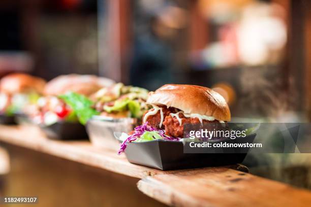 fresh crispy pork burgers in a row at food market - focus on foreground food stock pictures, royalty-free photos & images