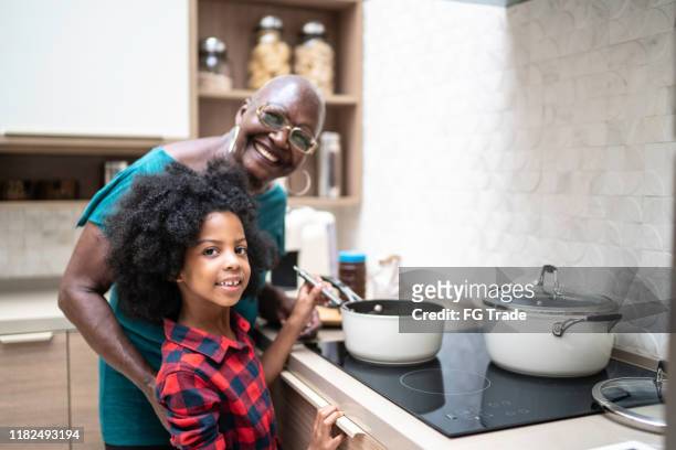祖母と一緒に甘い食べ物を準備/調理する孫娘の肖像画 - ガス台 ストックフォトと画像