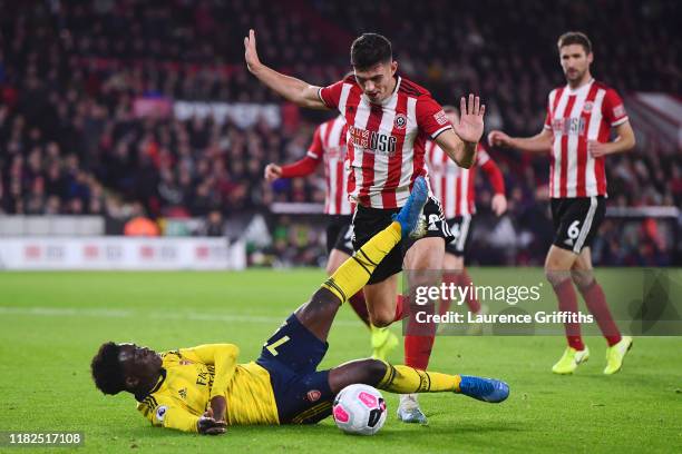 Bukayo Saka of Arsenal goes down after he battles for possession with John Egan of Sheffield United during the Premier League match between Sheffield...