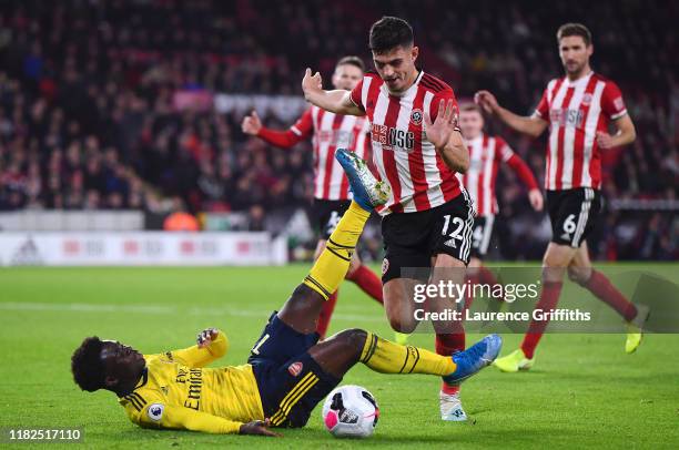 Bukayo Saka of Arsenal goes down after he battles for possession with John Egan of Sheffield United during the Premier League match between Sheffield...