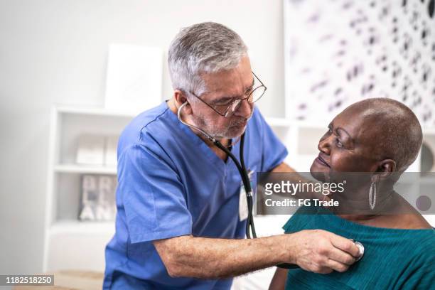 doctor using a stethoscope listen to the heartbeat of the elderly patient - human heart stock pictures, royalty-free photos & images