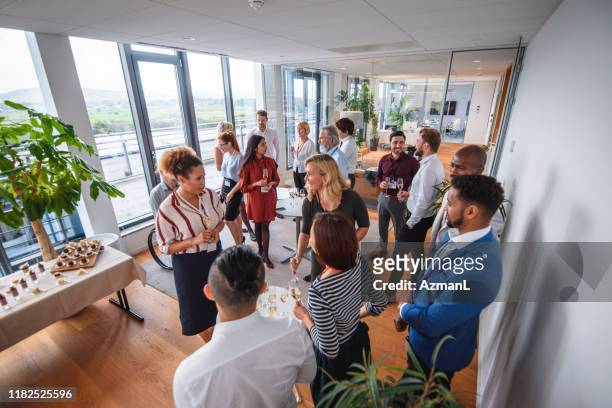 business colleagues enjoying sparkling wine and conversation - launch event stock pictures, royalty-free photos & images