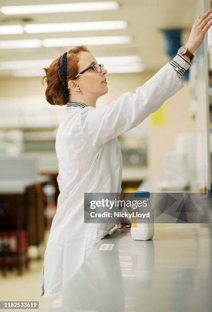 reaching to the chemicals on the rack - doctor reaching stock pictures, royalty-free photos & images