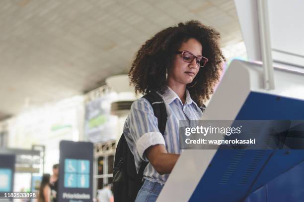 junge frau mit selbstbedienungs-check-in am flughafen - interactive kiosk stock-fotos und bilder