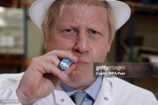 Britain's Prime Minister Boris Johnson eats a candy stick which reads "Back Boris" during a General Election campaign trail stop at Coronation Candy...