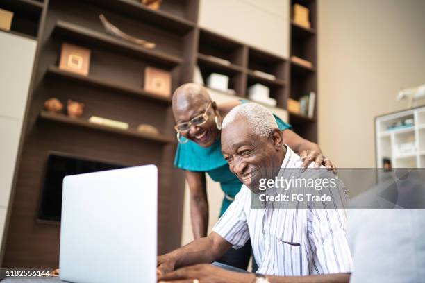 pareja mayor riendo mientras usa un ordenador portátil - old man afro fotografías e imágenes de stock
