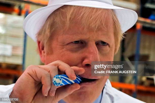 Britain's Prime Minister Boris Johnson eats a stick of rock with "Back Boris" written through it during a visit to Blackpool rock producer...