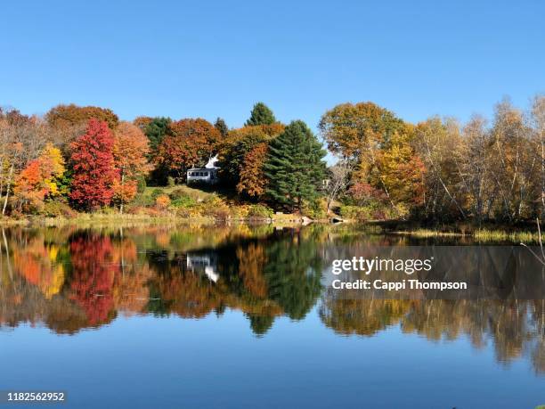 small house and autumn tree reflections near lake auburn, maine usa - lake auburn photos et images de collection