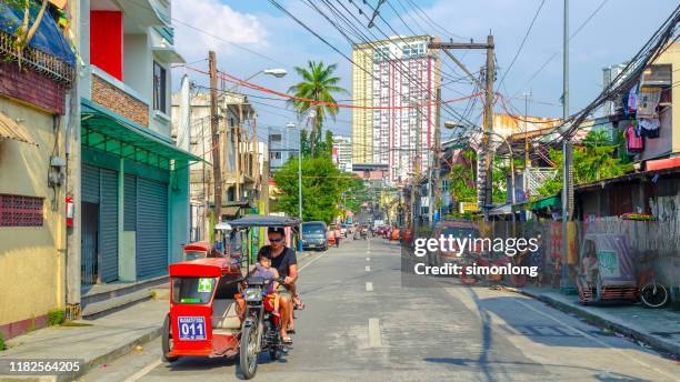father and kid ride tricycle on street - philippines tricycle stock pictures, royalty-free photos & images