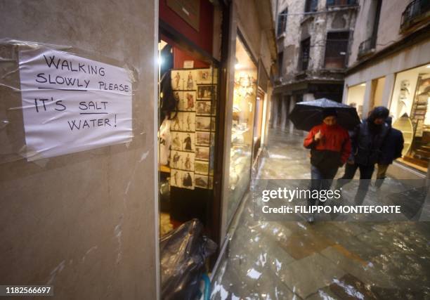 Placard hanging on the wall alert the people to walking slowly due the salt water in the flooded streets, on November 15, 2019 in Venice, two days...