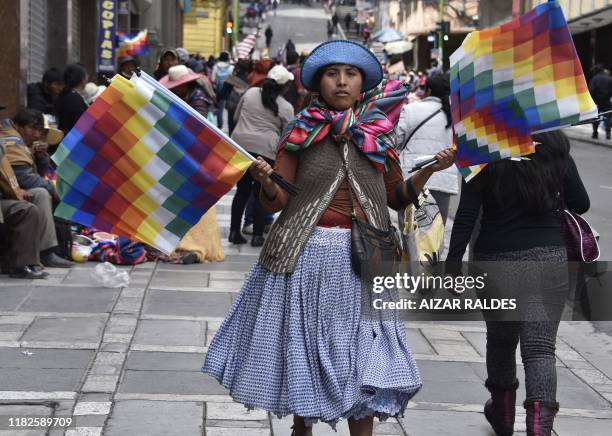 An Aymara indigenous woman sells Wiphala flags -representing native peoples- as supporters of Bolivian ex-President Evo Morales protest against the...