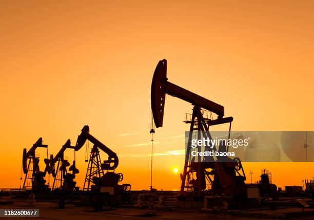 oil pumps and rig at sunset - crude oil stock pictures, royalty-free photos & images