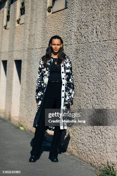 Model Binx Walton wears a black and white floral print jacket, black top, black pants, black Fendi bag, and black sneakers after the Salvatore...