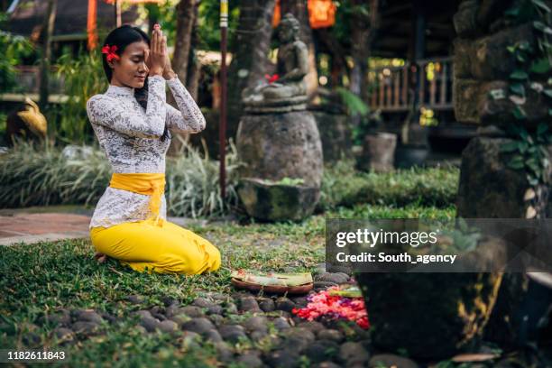 dame dans l'habillement indonésien traditionnel priant - cérémonie photos et images de collection