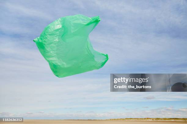 plastic bag flying in the wind on the beach against sky - plastic bag stock pictures, royalty-free photos & images