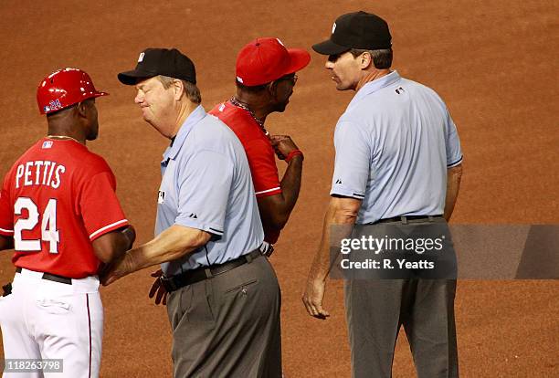 Umpire Joe West tries to calm first base coach Gary Pettis of the Texas Rangers while Manager Ron Washington debates the call made by first base...