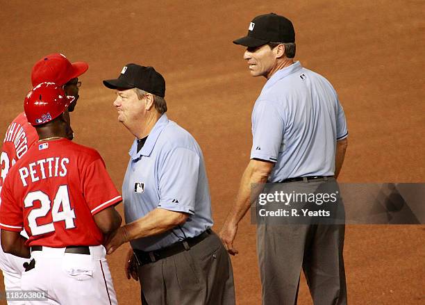 Umpire Joe West tries to calm Manager Ron Washington and first base coach Gary Pettis of the Texas Rangers for a call made by first base umpire Angel...