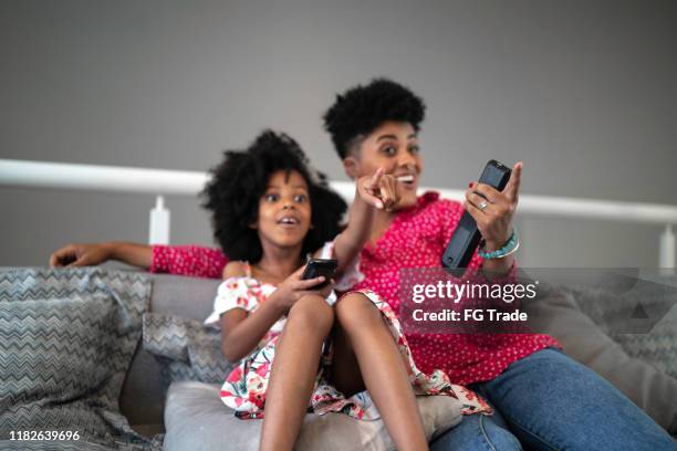 sister watching tv and pointing at it - voice remote stock pictures, royalty-free photos & images