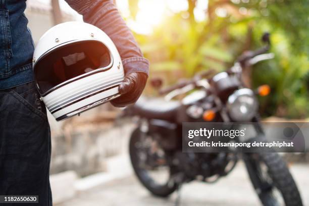 hand man holding a helmet and motorcycle blur background. - sports helmet stock pictures, royalty-free photos & images