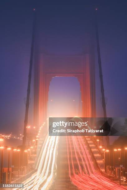 light trails on road at golden gate bridge over san francisco - golden gate bridge city fog stock-fotos und bilder