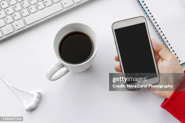 hand holding smart phone on white desk - input device stock pictures, royalty-free photos & images