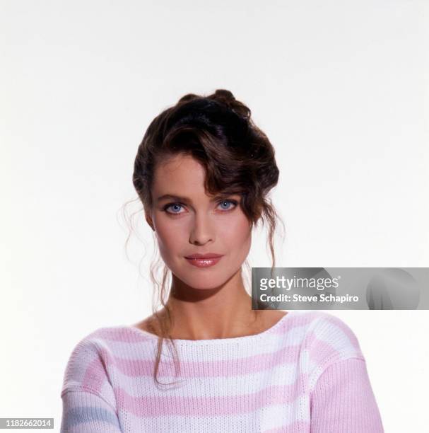 Portrait of American model and actress Carol Alt, in a blue, pink, and white sweater, as she poses against a white background, Los Angeles,...