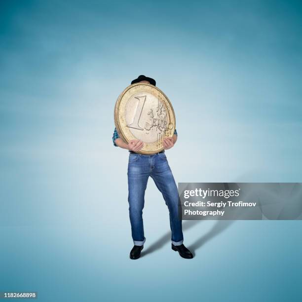 man holding big and heavy euro coin, financial concept - silver hat stock pictures, royalty-free photos & images