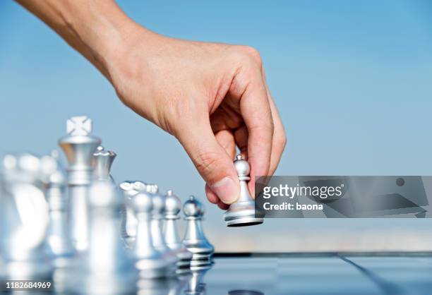 mão do homem que prende o peão de prata primeiro movimento - pawn chess piece - fotografias e filmes do acervo