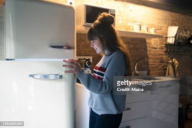 mädchen, das den kühlschrank öffnet, ist hungrig - fridge door stock-fotos und bilder
